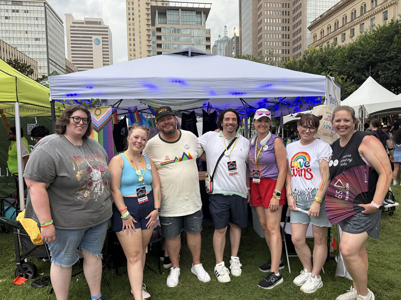 Group of people at Pride Event in Dallas. Seven individuals wearing t-shirts and shorts in a variety of colors during the day in downtown Dallas.